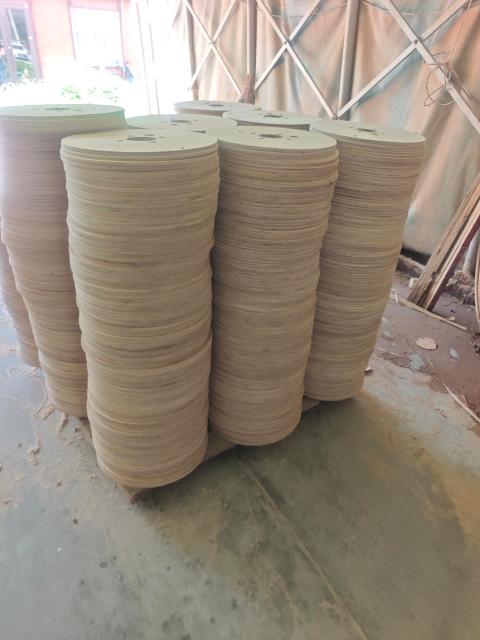 Plywood Cable Reel Flanges — Thin circular plywood discs stacked in tall columns in workshop